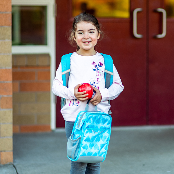 child with apple and school bag