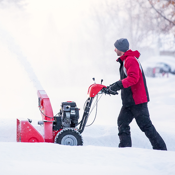 Man in red snowblowing