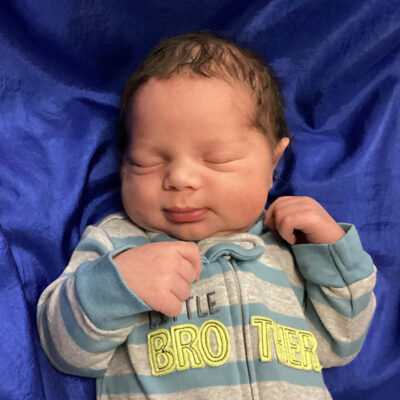 newborn baby in little brother onesie