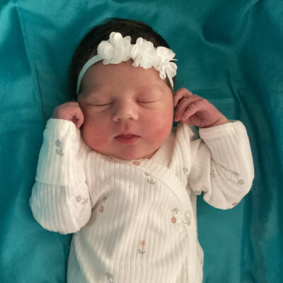 newborn baby in white onesie with white headband