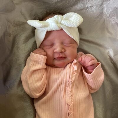 baby wearing peach onesie with a bow