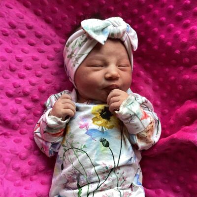 baby wearing floral onesie on bright pink blanket